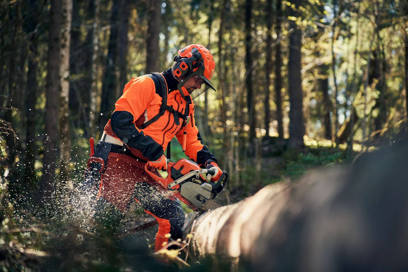 Skogsarbetare i Husqvarna skyddskläder med hjälm och visir