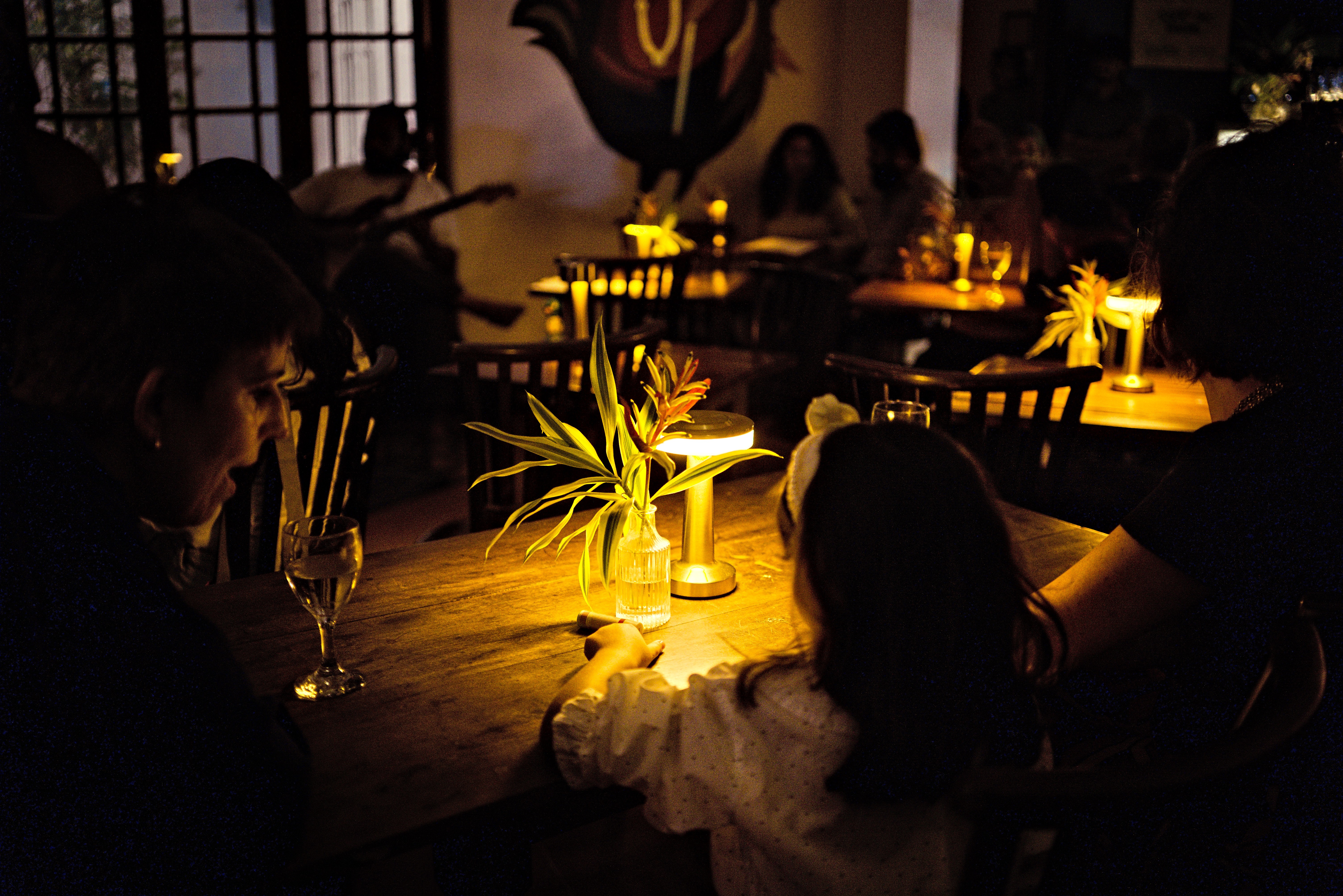 Guests around warmly lit Café tables during an evening at Black Cat