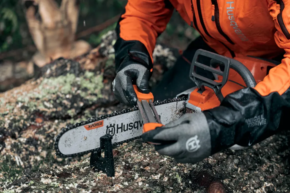 Händer som filar sågkedjan på en Husqvarna motorsåg